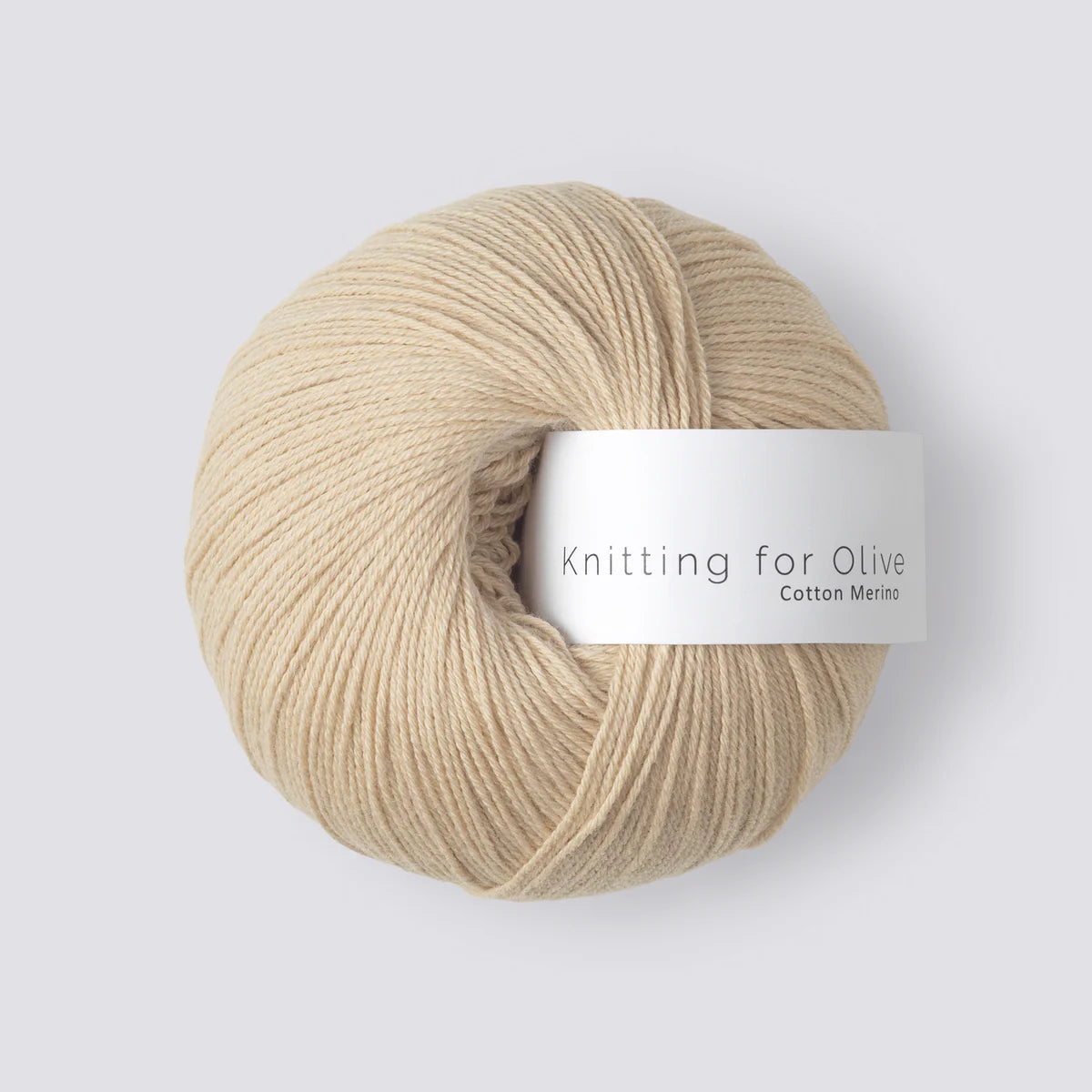 “Bol wol in de kleur ‘Wheat’ van Knitting for Olive, afkomstig uit de Cotton Merino-lijn, netjes opgerold met een wit label, gefotografeerd tegen een egale witte achtergrond – perfect voor zachte en natuurlijke breiprojecten.”