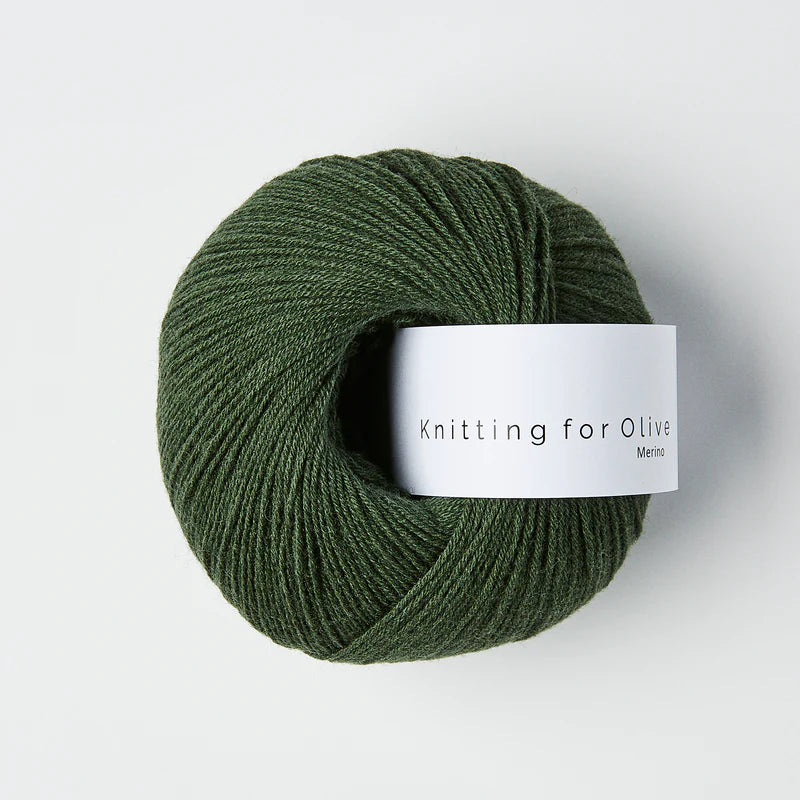 “Bol wol in de kleur ‘Bottle Green’ van Knitting for Olive, uit de Merino-lijn, netjes opgerold met wit label tegen een witte achtergrond – zacht, ademend en duurzaam garen.”