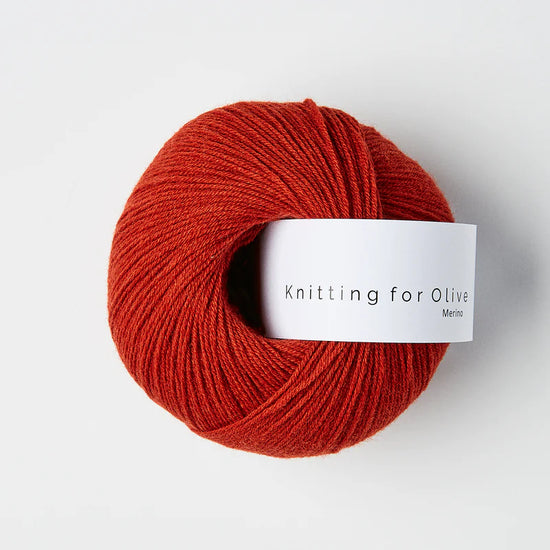 “Bol wol in de kleur 'Pomegranate' van Knitting for Olive, uit de Merino-lijn, netjes opgerold met wit label tegen een witte achtergrond – zacht, ademend en duurzaam garen.”