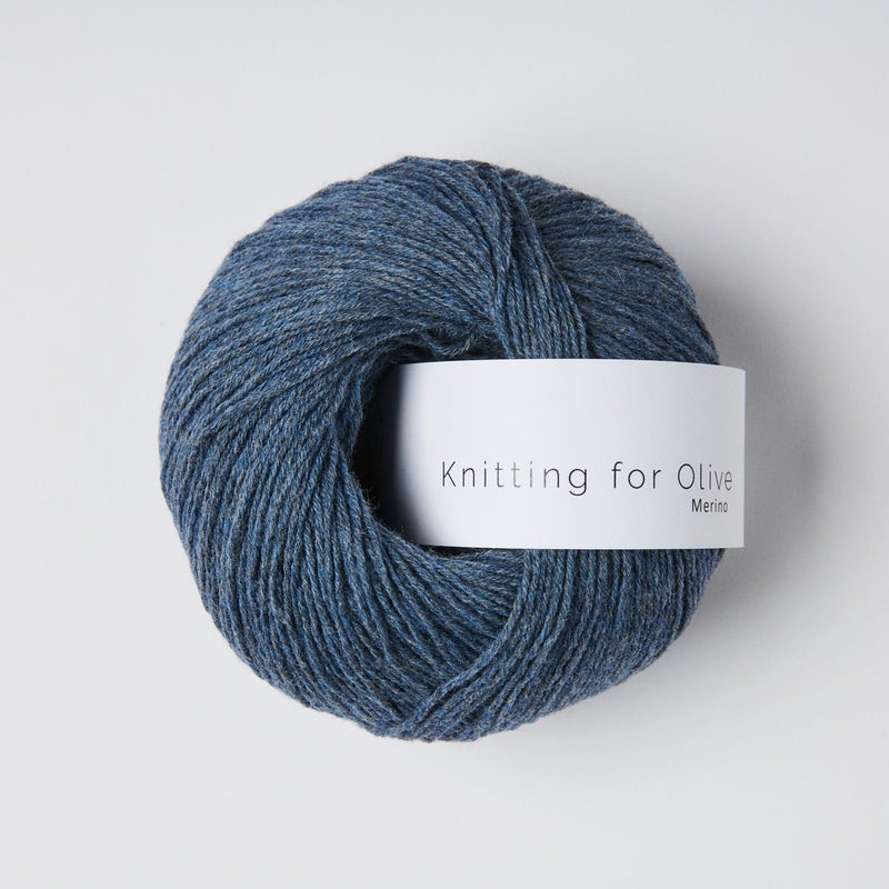 “Bol wol in de kleur ‘Blue Jeans’ van Knitting for Olive, uit de Merino-lijn, netjes opgerold met wit label tegen een witte achtergrond – zacht, ademend en duurzaam garen."