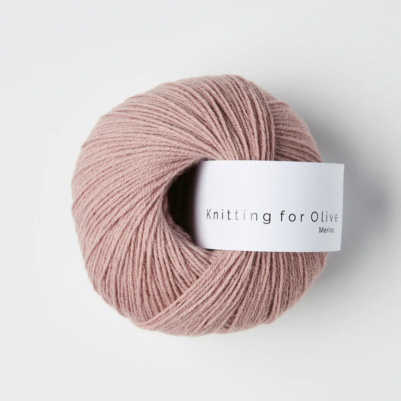 “Bol wol in de kleur ‘Dusty Rose’ van Knitting for Olive, uit de Merino-lijn, netjes opgerold met wit label tegen een witte achtergrond – zacht, ademend en duurzaam garen.”