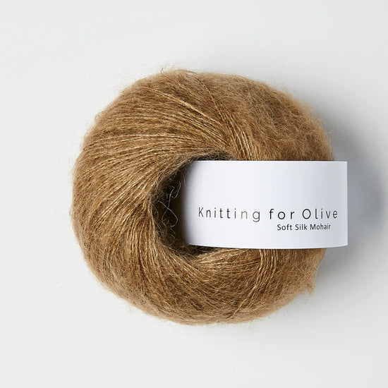 “Bol wol in de kleur ‘Nut Brown’ van Knitting for Olive, uit de Soft Silk Mohair-lijn, pluizig en luchtig opgerold met een wit label tegen een witte achtergrond – luxe en duurzaam garen van mohair en zijde.”