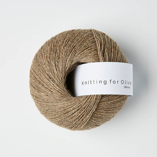 “Bol wol in de kleur ‘Cardamom van Knitting for Olive, uit de Merino-lijn, netjes opgerold met wit label tegen een witte achtergrond – zacht, ademend en duurzaam garen.”