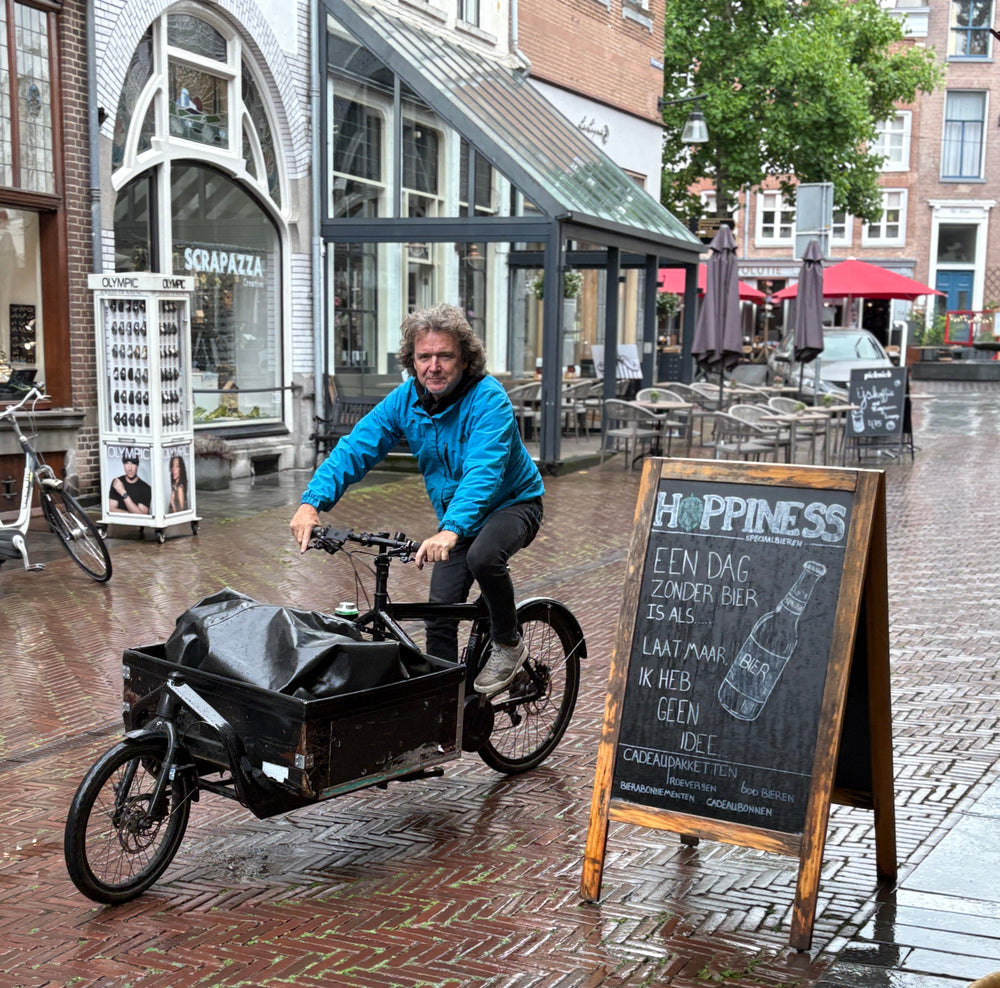 Fietskoerier op een bakfiets in het centrum van Zutphen, onderweg met een duurzame bezorging van wolwinkel Ons Lykke.