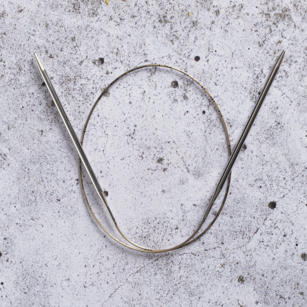 Addi rondbreinaald van 80 cm met glanzende metalen punten en goudkleurige kabel, liggend op een grijze stenen ondergrond.