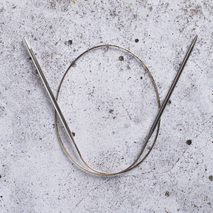 Addi rondbreinaald van 80 cm met glanzende metalen punten en goudkleurige kabel, liggend op een grijze stenen ondergrond.