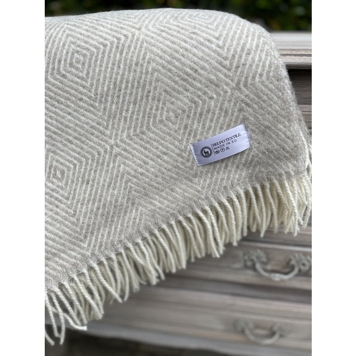 Beige wollen plaid met subtiel patroon en franjes, close-up van het Belpo Textile-label op houten achtergrond.