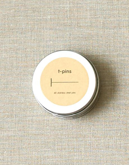 Blikje Cocoknits T-pins van roestvrij staal op een linnen ondergrond, verpakt in een ronde metalen tin.