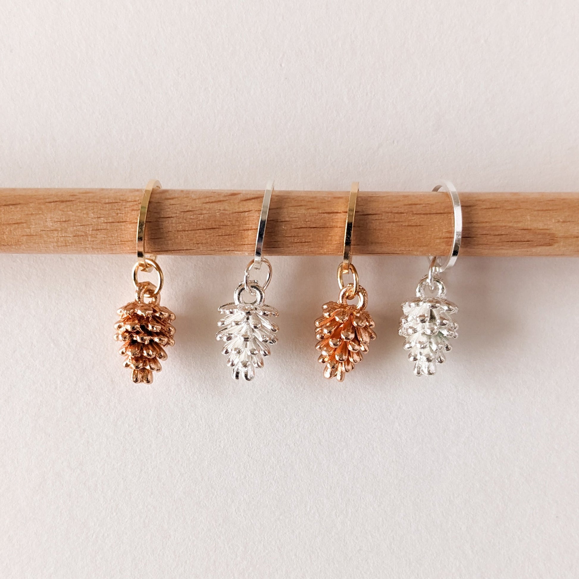 Steekmarkeerders van Hello Kim met dennenappels in goud en zilver, een warme en natuurlijke toevoeging aan je breiwerk.