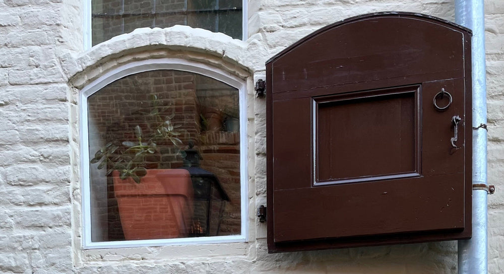Detail van een oud venster met houten luik en plantenpot in het historische centrum van Zutphen, vlak bij wolwinkel Ons Lykke.