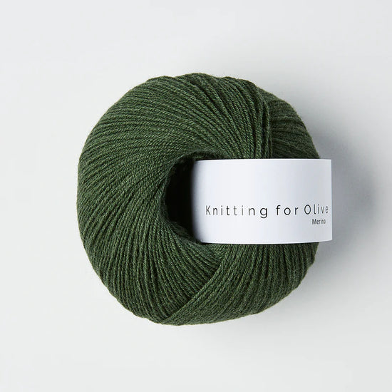 “Bol wol in de kleur ‘Bottle Green’ van Knitting for Olive, uit de Merino-lijn, netjes opgerold met wit label tegen een witte achtergrond – zacht, ademend en duurzaam garen.”