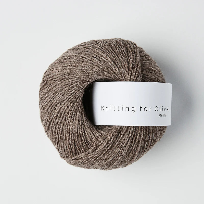 “Bol wol in de kleur ‘Hazel’ van Knitting for Olive, uit de Merino-lijn, netjes opgerold met wit label tegen een witte achtergrond – zacht, ademend en duurzaam garen.”