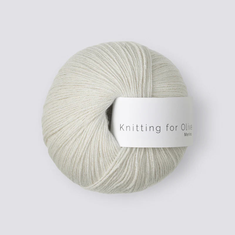 “Bol wol in de kleur ‘Limestone’ van Knitting for Olive, uit de Merino-lijn, netjes opgerold met wit label tegen een witte achtergrond – zacht, ademend en duurzaam garen.”