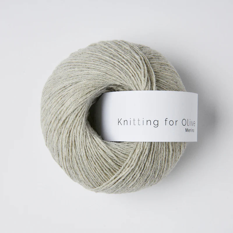 “Bol wol in de kleur ‘Morning Haze’ van Knitting for Olive, uit de Merino-lijn, netjes opgerold met wit label tegen een witte achtergrond – zacht, ademend en duurzaam garen.”