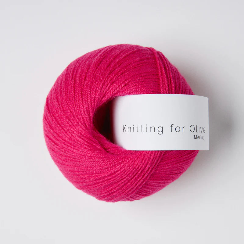 “Bol wol in de kleur ‘Pink Daisies’ van Knitting for Olive, uit de Merino-lijn, netjes opgerold met wit label tegen een witte achtergrond – zacht, ademend en duurzaam garen.”