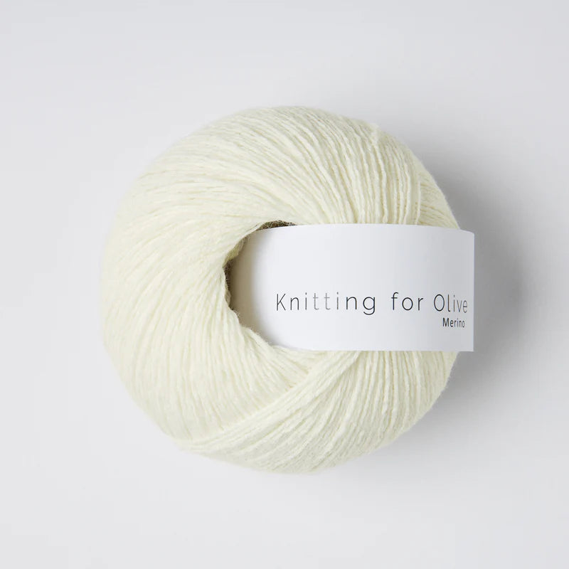 “Bol wol in de kleur ‘Snowflake’ van Knitting for Olive, uit de Merino-lijn, netjes opgerold met wit label tegen een witte achtergrond – zacht, ademend en duurzaam garen.”