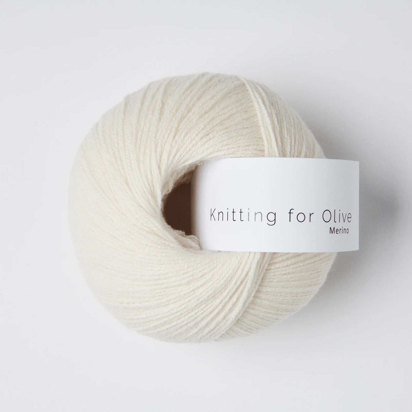 “Bol wol in de kleur ‘Cream’ van Knitting for Olive, uit de Merino-lijn, zorgvuldig opgerold met een wit label tegen een witte achtergrond – een zachte, lichte en natuurlijke kleur voor tijdloze breiprojecten.”