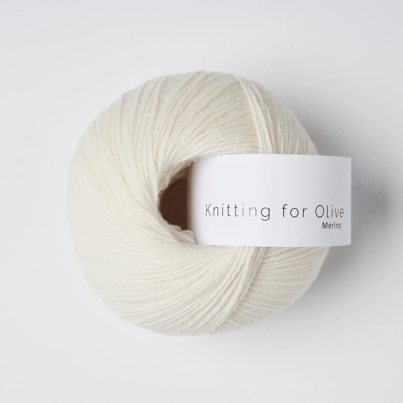 “Bol wol in de kleur ‘Cream’ van Knitting for Olive, uit de Merino-lijn, zorgvuldig opgerold met een wit label tegen een witte achtergrond – een zachte, lichte en natuurlijke kleur voor tijdloze breiprojecten.”