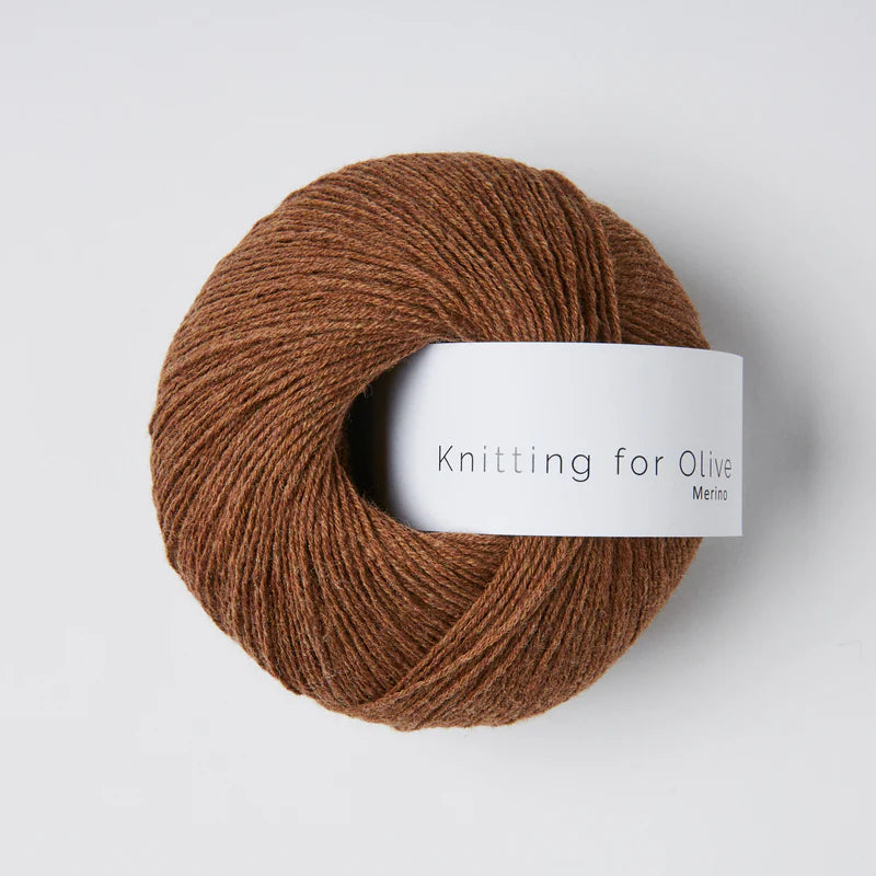 “Bol wol in de kleur ‘Dark Cognac’ van Knitting for Olive, uit de Merino-lijn, netjes opgerold met wit label tegen een witte achtergrond – zacht, ademend en verantwoord garen.”
