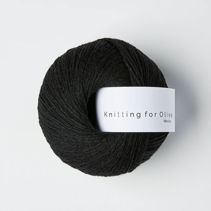 “Bol wol in de kleur ‘Licorice’ van Knitting for Olive, uit de Merino-lijn, netjes opgerold met wit label tegen een witte achtergrond – zacht, ademend en duurzaam garen.”