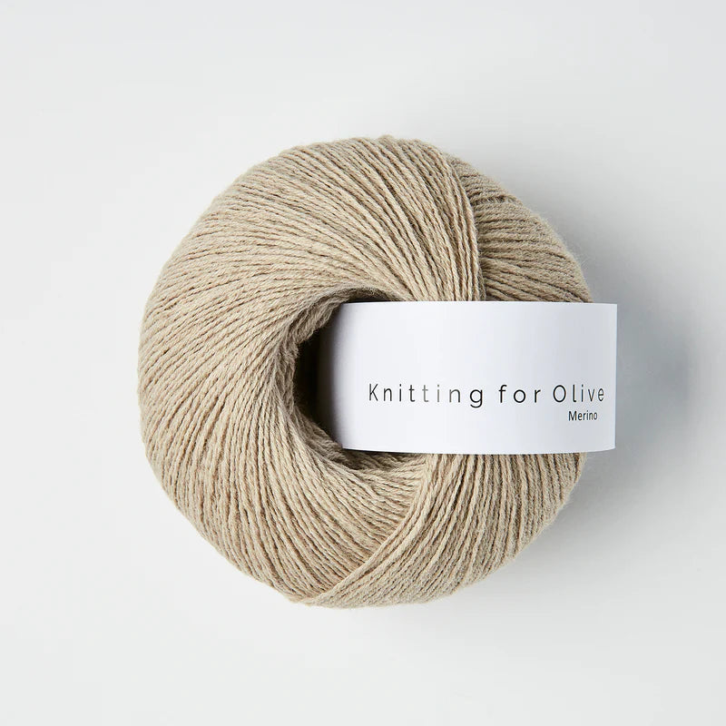 “Bol wol in de kleur ‘Oatmeal’ van Knitting for Olive, uit de Merino-lijn, netjes opgerold met wit label tegen een witte achtergrond – zacht, ademend en duurzaam garen.”