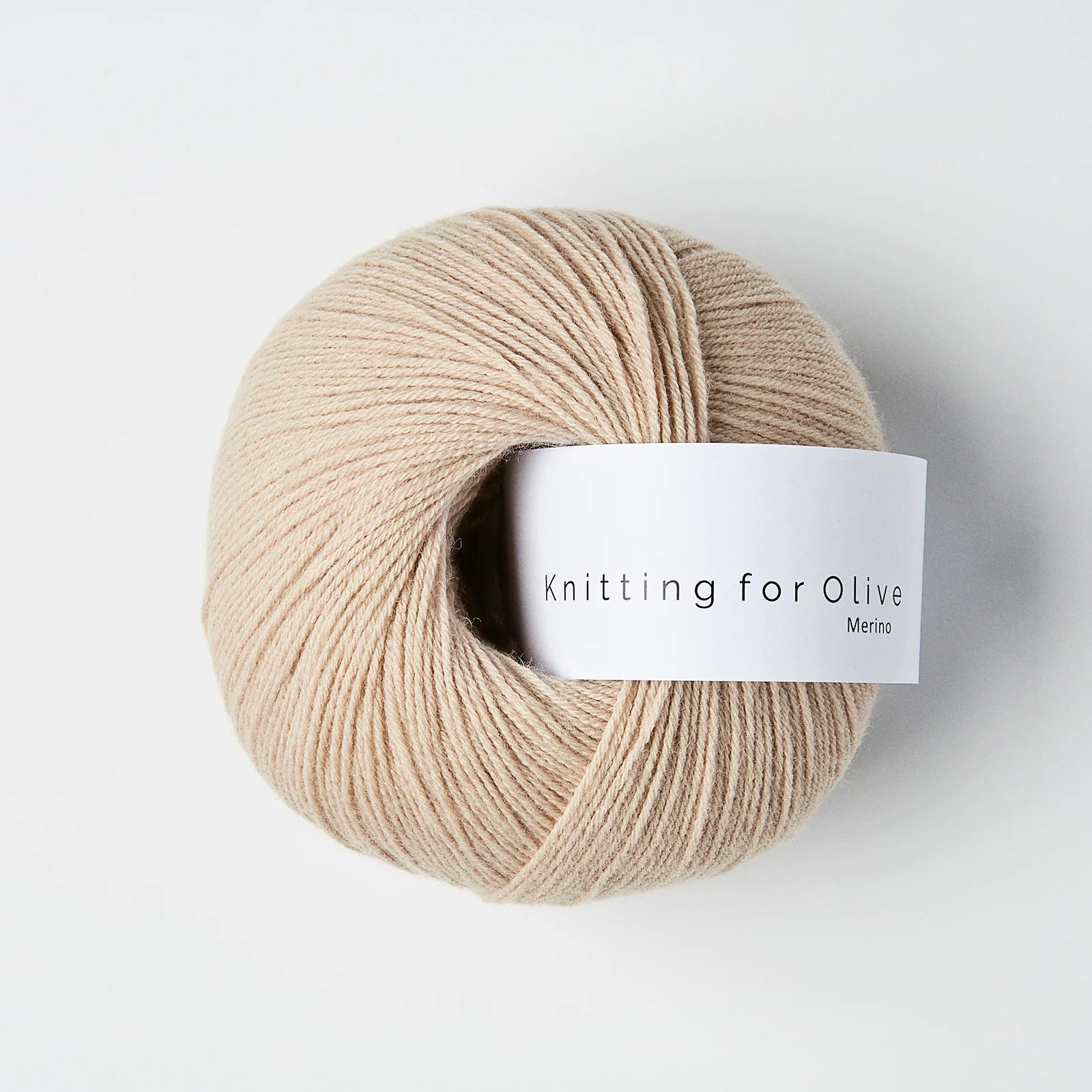 “Bol wol in de kleur ‘Powder’ van Knitting for Olive, uit de Merino-lijn, elegant opgerold met wit label tegen een witte achtergrond – zacht, licht en perfect voor fijne breiprojecten.”