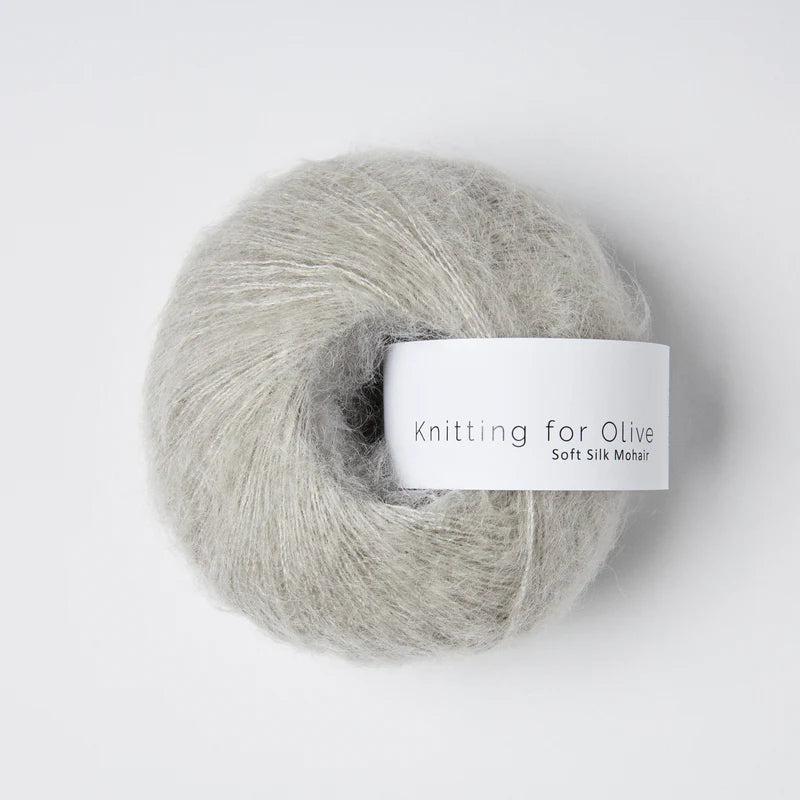 “Bol wol in de kleur 'Morninghaze' van Knitting for Olive, uit de Soft Silk Mohair-lijn, pluizig en luchtig opgerold met een wit label tegen een witte achtergrond – luxe en duurzaam garen van mohair en zijde.”