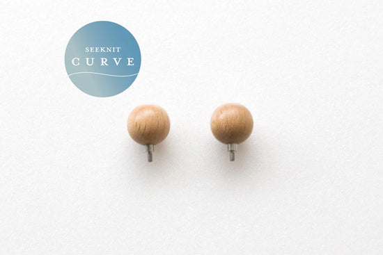 Twee houten Seeknit Curve Stoppers met metalen schroefdraad op een lichte achtergrond. Geschikt voor M1.8 kabels om steken veilig af te sluiten.