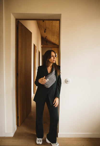 Vrouw met Gabrielle Paris Waistbag in Vichy Black, gedragen schuin over de schouder. Stijlvolle zwart-witte katoenen heuptas met tijdloze uitstraling.